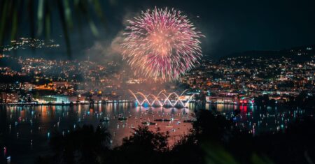 Buntes Feuerwerk explodiert über einem Schweizer See und spiegelt sich im Wasser